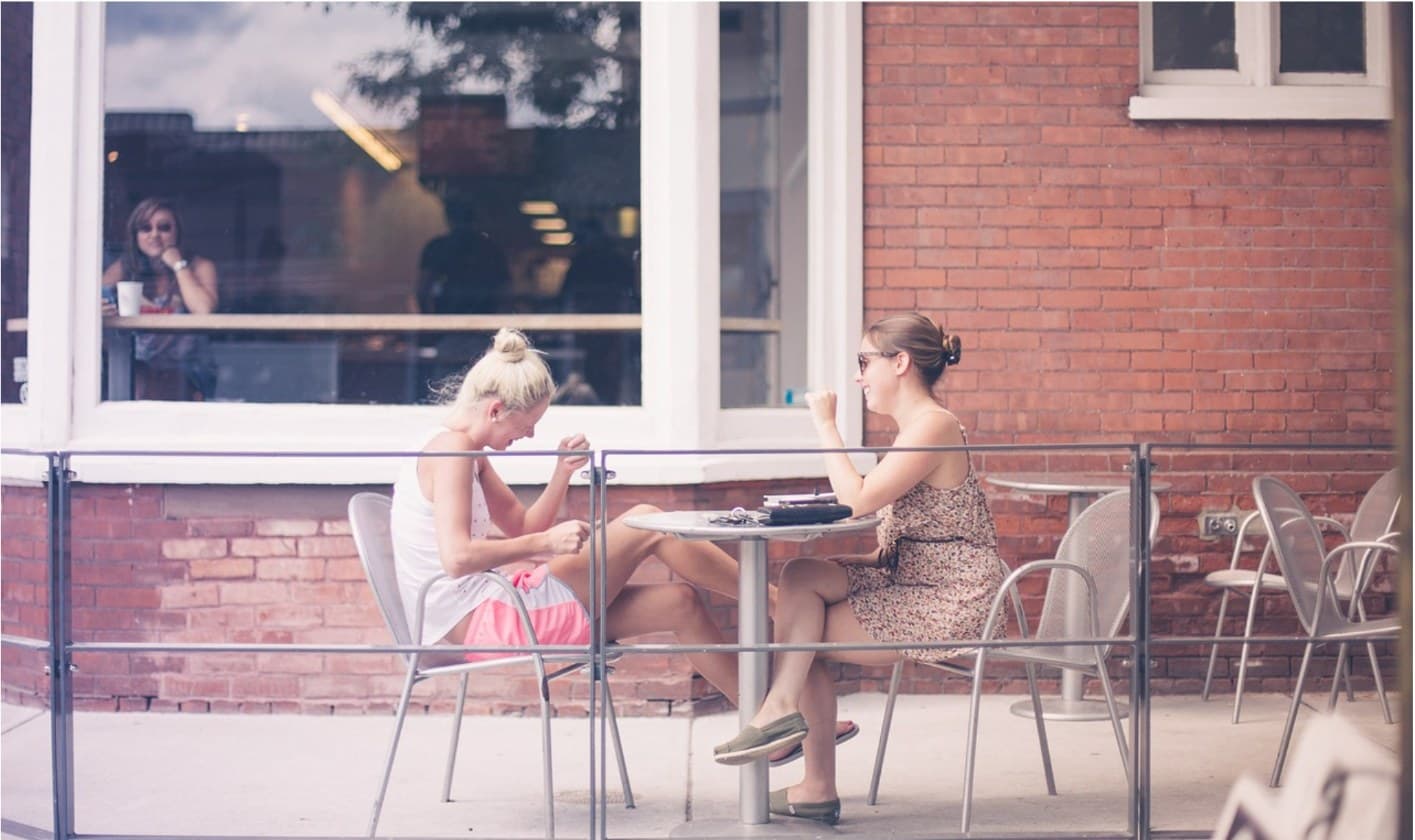 Two friends talking at an outdoor café table